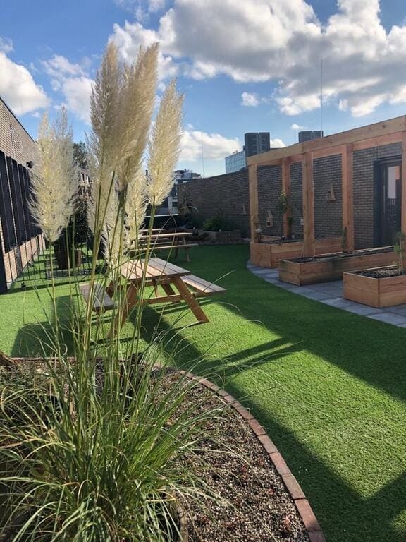 Dakterras met een natuurlijke border, kunstgras en een picknicktafel